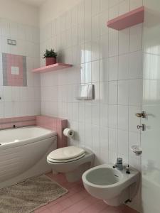 y baño blanco y rosa con aseo y lavamanos. en Appartamento Gli Ulivi, 