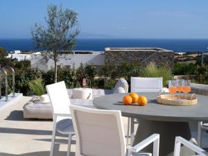 a table and chairs with oranges on top of a patio at Villa Le22, 180 panoramic sea views, Paros in Kampos Paros