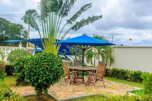 a patio table and chairs with a blue umbrella at Mjengoni Annex in Tanga +4 photos