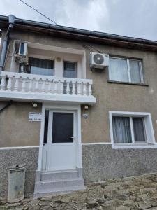 Casa con puerta blanca y balcón en Къща за гости Пантови, en Grammatikovo