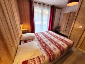 Schlafzimmer mit einem Bett mit einer roten und weißen Decke in der Unterkunft Appartement Les Gets, 3 pièces, 6 personnes - FR-1-598-76 in Les Gets