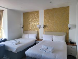 two beds in a hotel room with white sheets at Atlantic Seafront in Brighton & Hove