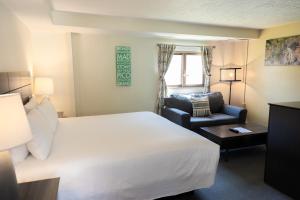 a hotel room with a bed and a chair at Clear River Inn and Tavern in Pittsfield