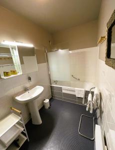 ein Badezimmer mit einem Waschbecken und einer Badewanne in der Unterkunft Le Vauban in Merville-Franceville-Plage