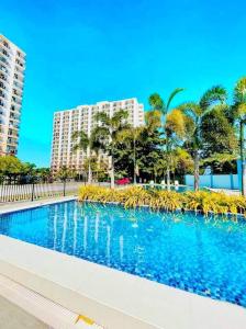 a large swimming pool with palm trees and buildings at Haus of Emerald Studio Condo - Saekyung 956 Looc in Cebu City
