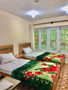 Al Jannat Hotel & Relax Inn Guest House Skardu في سكردو: غرفة نوم بسريرين ونافذة