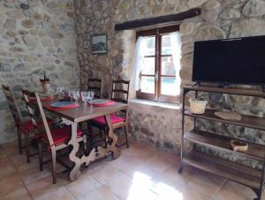 a dining room with a table with chairs and a television at lou caladou gîte en pierre avec bain à remous in Vallon-Pont-dʼArc