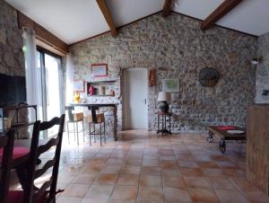 a room with a stone wall with a table and chairs at lou caladou gîte en pierre avec bain à remous in Vallon-Pont-dʼArc