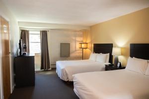 a hotel room with two beds and a television at Clear River Inn and Tavern in Pittsfield