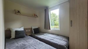 a bedroom with two beds and a window at MobilHome Marie EUROPAPARK 20min in Boofzheim