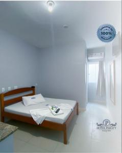 um pequeno quarto com uma cama com lençóis brancos em Hotel Paraty em Camaçari