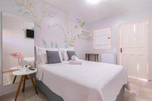 a white bedroom with a white bed and a table at Pousada Lara in Pirenópolis