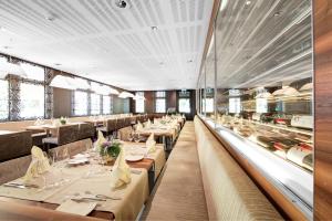 a dining room with tables and chairs and windows at Hotel Krone Sarnen in Sarnen