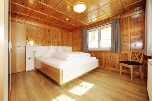 een slaapkamer met een wit bed in een houten kamer bij Aktiv-Ferienwohnungen Montafon in Sankt Gallenkirch