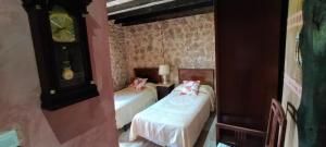 a bedroom with two beds and a clock on the wall at Algarabiastaying 3 granja San Julián in Medina de Pomar