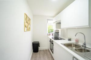 a white kitchen with a sink and a counter at Modern Apt with Free Parking & Park Views in MK in Woolstone