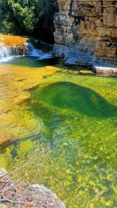 une piscine d'eau verte avec une cascade dans l'établissement Paraiso na beira de cachoeiras Canyons Capitólio MG, à Guapé
