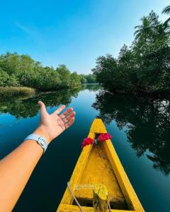a person is waving from a boat on a river at Honnavar Pauli s Homestay in Honāvar
