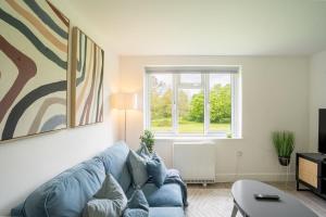 a living room with a blue couch and a window at Modern Apt with Free Parking & Park Views in MK in Woolstone