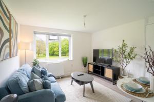 a living room with a blue couch and a tv at Modern Apt with Free Parking & Park Views in MK in Woolstone