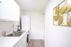 a white kitchen with a sink and a refrigerator at Modern Apt with Free Parking & Park Views in MK in Woolstone