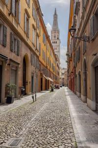 een geplaveide straat in een stad met een klokkentoren bij Home In The Heart Of Ghirlandina in Modena