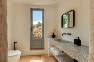 a bathroom with a sink and a toilet and a mirror at Torretta Le Feritoie - piscina e terrazza vista mare in Fasano