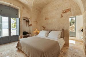 a bedroom with a large bed in a stone wall at Torretta Le Feritoie - piscina e terrazza vista mare in Fasano