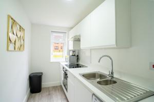 a kitchen with white cabinets and a sink at Modern Apt with Free Parking & Park Views in MK in Woolstone