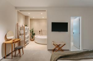 a bedroom with a bathroom with a tub and a tv at Trizonia Mare Suites in Trizonia