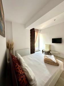 a bedroom with a bed and a window and a chair at Coral Residence -Mamaia Nord in Mamaia