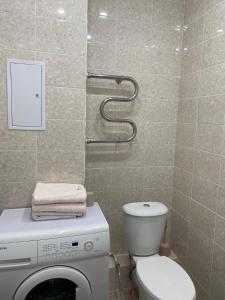 a bathroom with a toilet and a washing machine at 1-комнатная комфортная кухня-студия со всеми удобствами in Kostanay