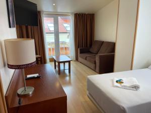 um quarto de hotel com uma cama e um sofá em Hotel Spa Playa Langosteira by Adeloló em Finisterre