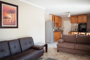 uma sala de estar com dois sofás e uma cozinha em Sun Ray Guest House em Centurion