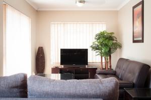 sala de estar con sofá y TV en Sun Ray Guest House, en Centurion