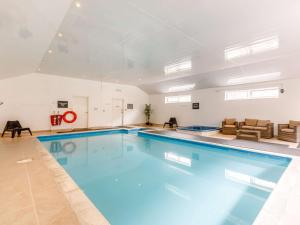 a large swimming pool with blue water in a building at 1 Bed in Combe Martin PARSC in Berrynarbor