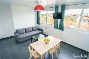 a living room with a table and a couch at Escale-marne fr - 202 - Free Parking - Free Luggage Storage - Metro 8 Eiffel Tower - All equipped - Linen Included - Washing Machine - Panoramic View - From 1 to 18 guests in Maisons-Alfort