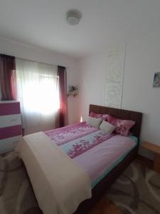 een slaapkamer met een groot bed met roze lakens bij Apartman Maja in Trebinje