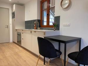 a kitchen with a black table and black chairs at L'Adresse Studio Rempart sud - centre historique Eguisheim in Eguisheim +28 photos