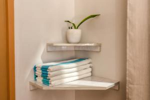 a stack of towels on a shelf with a plant at Ocean Pearl Maldives at Gulhi Island in Gulhi