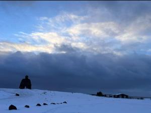 a person standing on top of a snow covered hill at Nonholl country cottage - Perfect getaway in Arnarstapi
