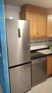 einen Kühlschrank aus Edelstahl in einer Küche mit Holzschränken in der Unterkunft Atico Duplex 1ª in Xilxes