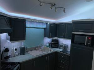 a kitchen with black cabinets and a counter top at JSNHolidays@CraigTara in Ayr