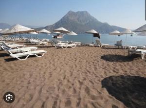 a sandy beach with chairs and umbrellas and the ocean at Adrasan Luna Aicha 1 in Adrasan