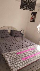 Una cama con escritura rosa en un dormitorio en chambre rez de chaussée SDB privée, salon et cuisine partagés, en Ferques