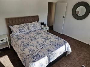 a bedroom with a blue and white bed and a mirror at Palms on Bruntwood in Tamahere