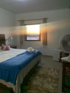 um quarto com uma cama, uma ventoinha e uma janela em Hospedagem vicentina em Tiradentes