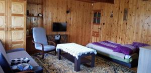 een slaapkamer met een bed, een stoel en een tafel bij Domki Pod Lasem in Macharce