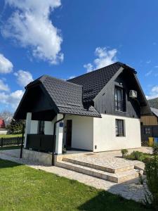 een klein wit huis met een zwart dak bij Plitvice Apis in Korenica