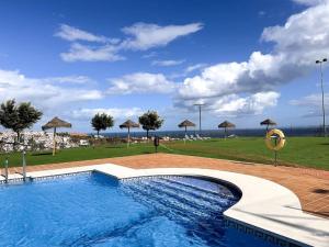 una piscina con sombrillas y un campo de césped en Sea Apartment 3Bed Small Oasis, en Castillo de Sabinillas